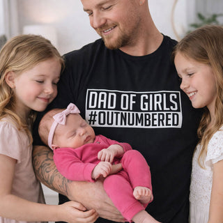 Dad wearing Dad of Girls outnumbered t-shirt holding baby with daughters, Father’s Day gift