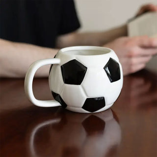 Football-shaped ceramic mug filled with coffee on a wooden table