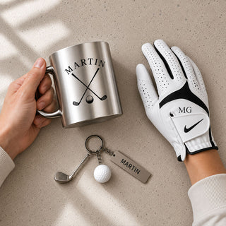 Person holding engraved silver golf mug beside personalised Nike golf glove and keyring