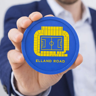 Man holding a flexible washable Leeds United Elland Road stadium coaster, blue and yellow football gift for Leeds fans