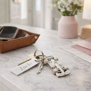 Personalised Formula 1 car keyring with engraved name tag and house keys on a white marble hallway table with leather tray and pink vase