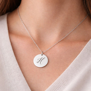 Personalised silver disc necklace with custom initial letter pendant worn around the neck