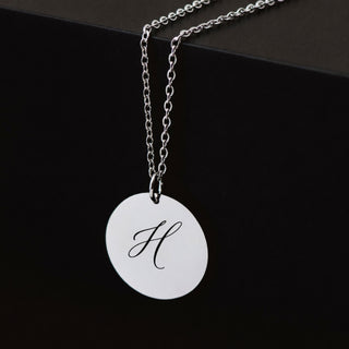 Personalised silver disc necklace with engraved H initial pendant on dark background
