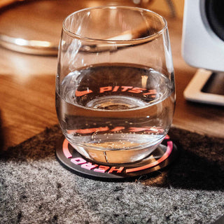 Pitstop Hero Formula 1 inspired racing wheel drink coaster holding a glass of water on a desk – motorsport themed coaster for F1 fans and racing enthusiasts