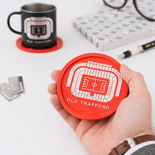 Man holding red Old Trafford stadium silicone coaster with Manchester football design, mug in background
