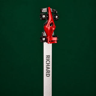 A close-up studio shot of a personalized F1 bookmark. With a red F1 car, and engraved metal bookmark